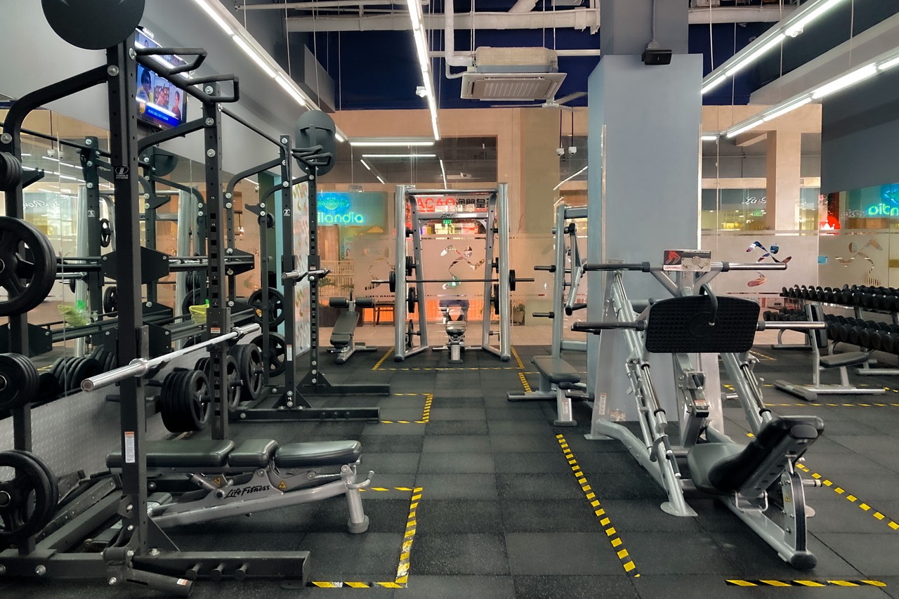A spacious gym featuring modern exercise equipment and weights, ideal for fitness routines.